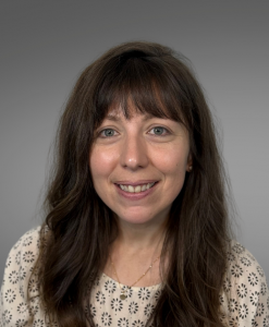 female, brown hair, white blouse, gray background