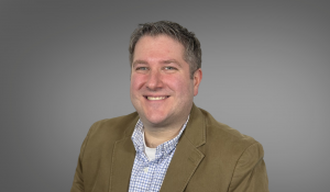 Male, brown jacket, checkered shirt, gray background