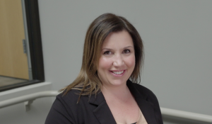 Female, gray background, in stairwell, black jacket, brown hair